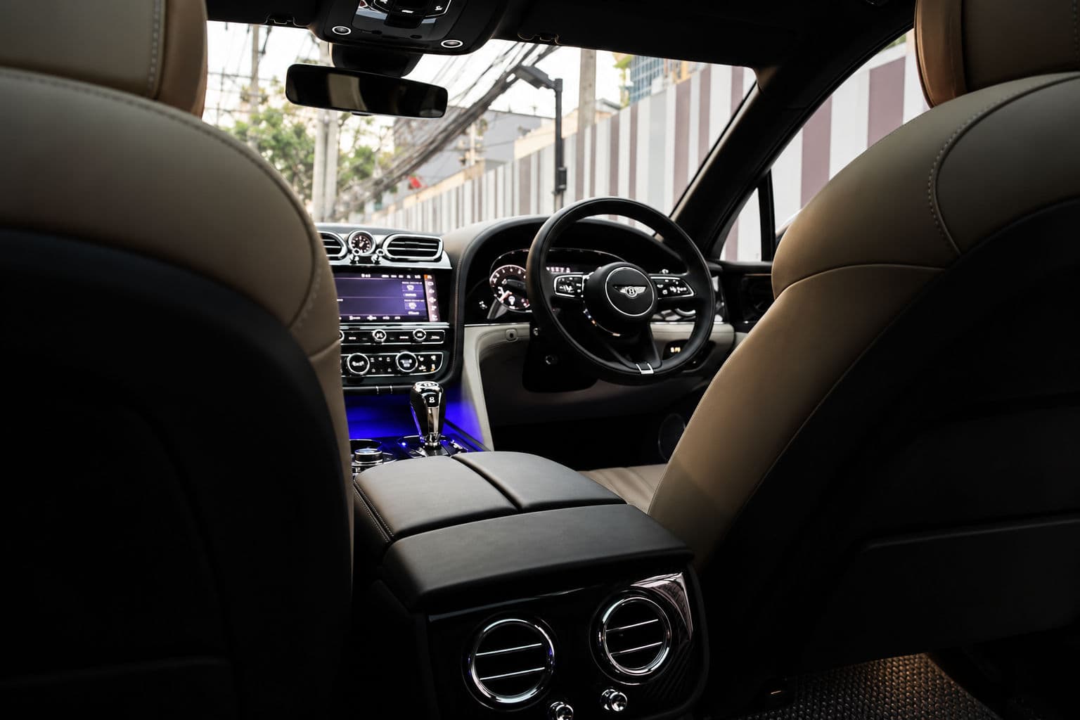 Bentayga V8 First Edition: Bentley Bentayga V8 First Edition 2023 cream and black leather interior, viewed from the rear seats toward the dashboard and right-hand-drive steering wheel.