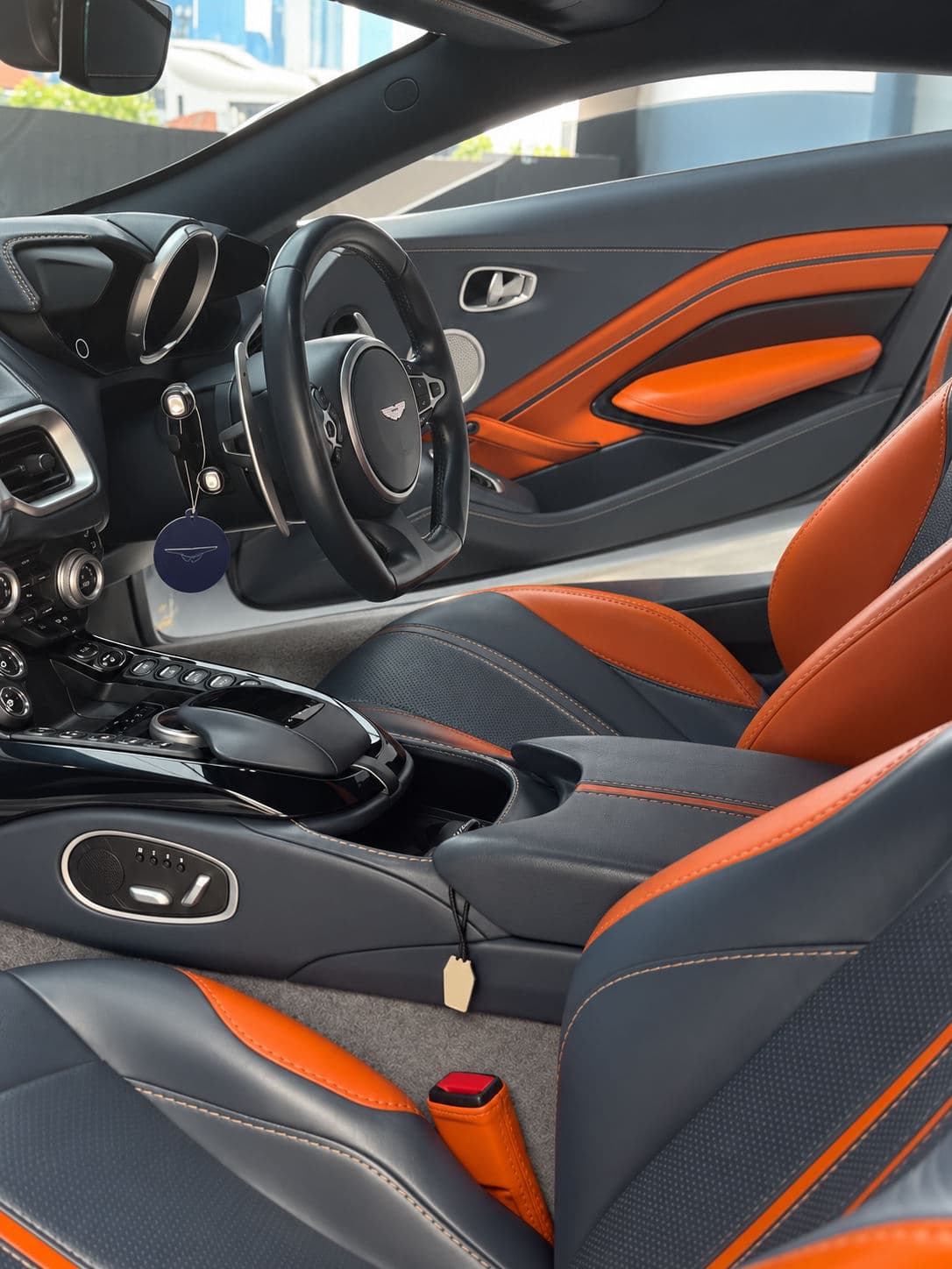 Vantage: Aston Martin Vantage 2024 interior viewed from the passenger side, showing black and orange leather seats, matching door trim, a right-hand-drive steering wheel and the centre console