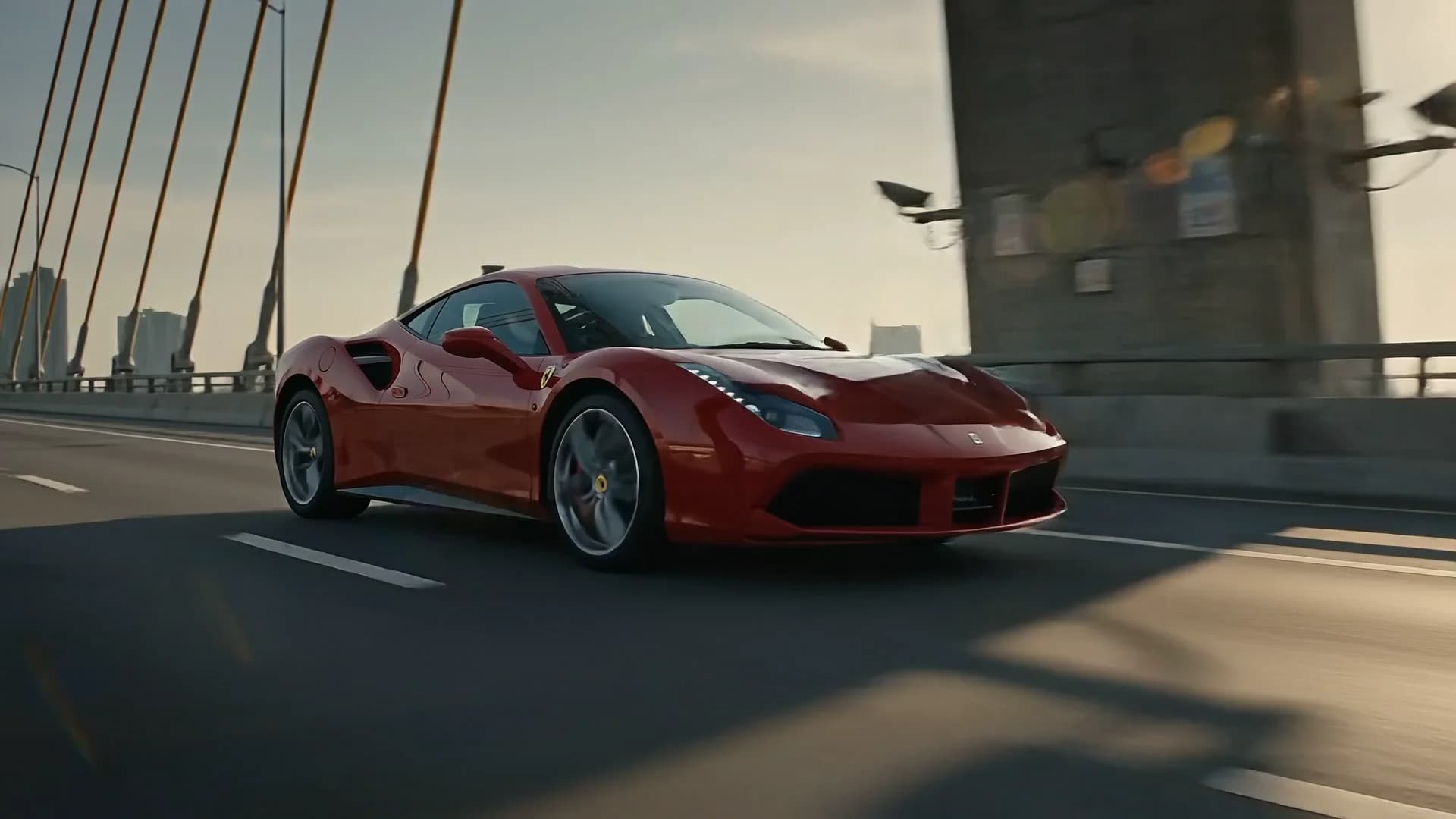 Red Ferrari 488 GTB driving across a cable-stayed bridge, front three-quarter view — RC24.