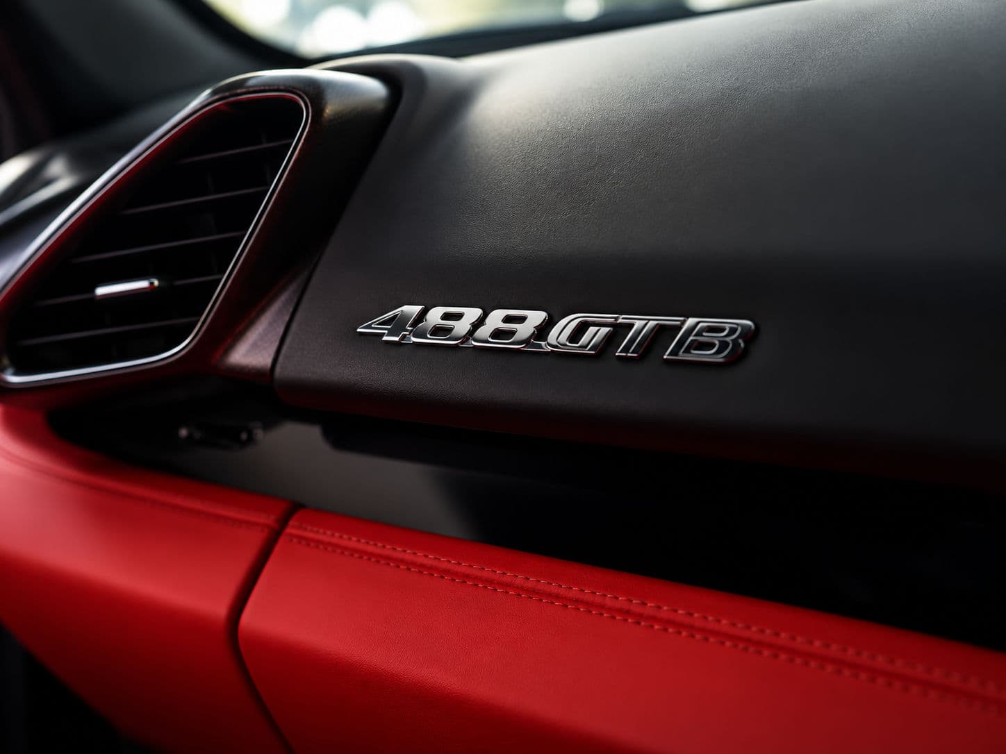 488 GTB: Close-up of Ferrari 488 GTB interior with model badge on the dashboard and red leather trim — RC24.