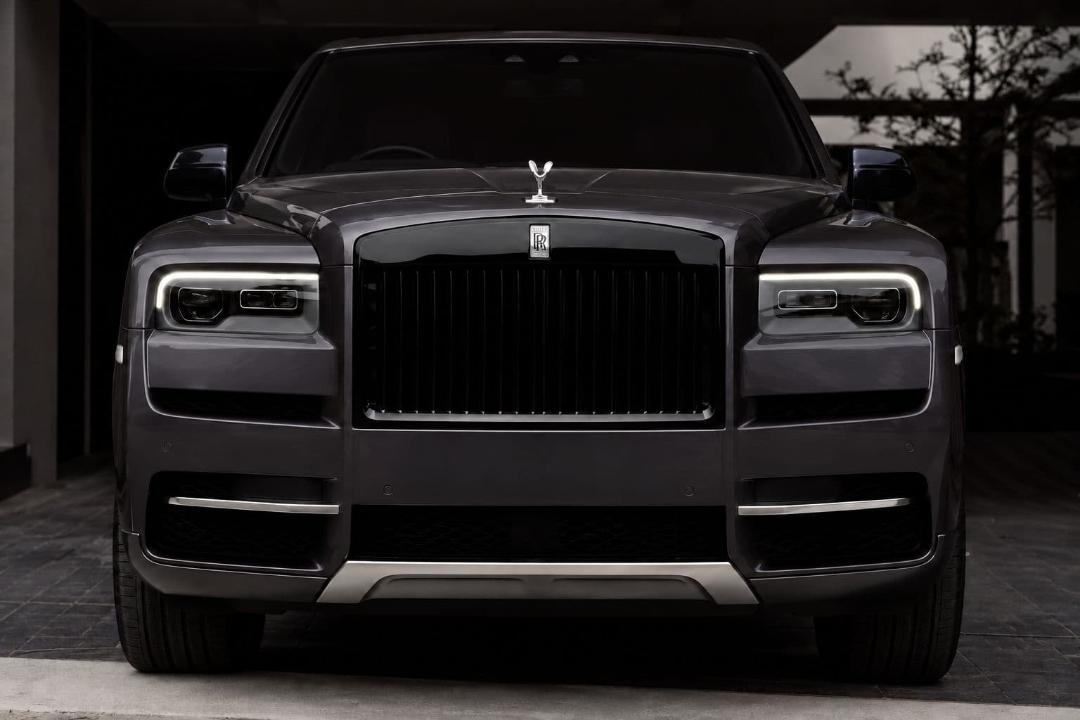 Cullinan: Rolls-Royce Cullinan 2024 in grey, direct front view with illuminated headlights — RC24
