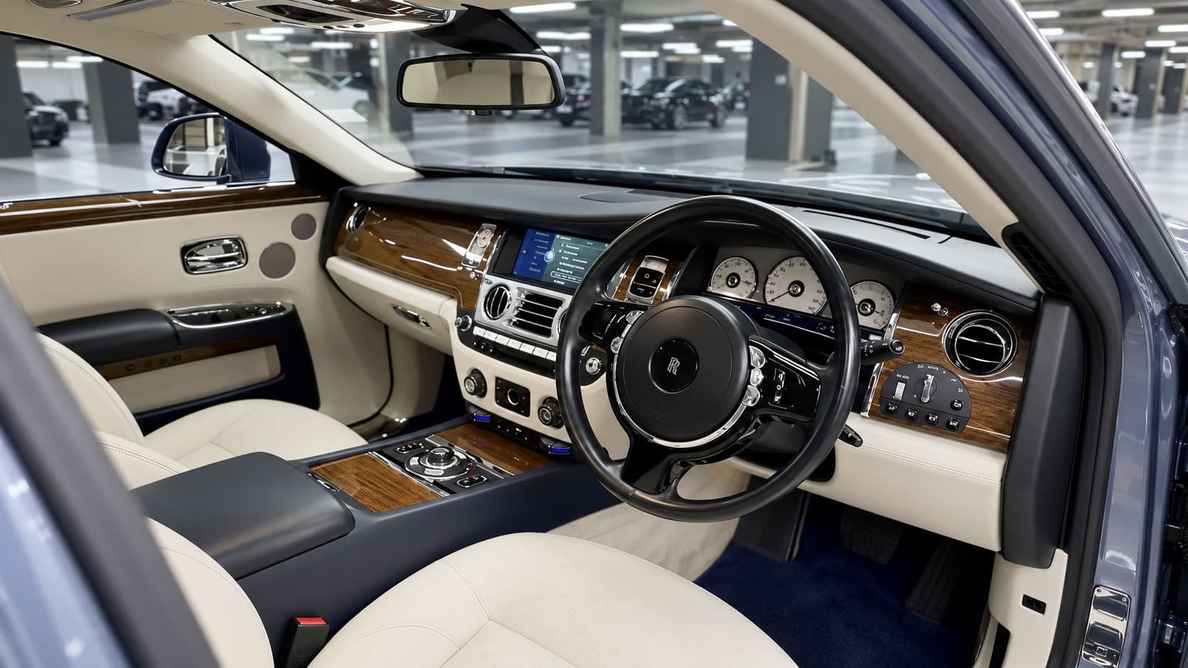 Ghost: Rolls-Royce Ghost 2019 front cabin, cream leather seats and dark blue trim, open-pore wood fascia and right-hand-drive steering wheel, view from the open front passenger door