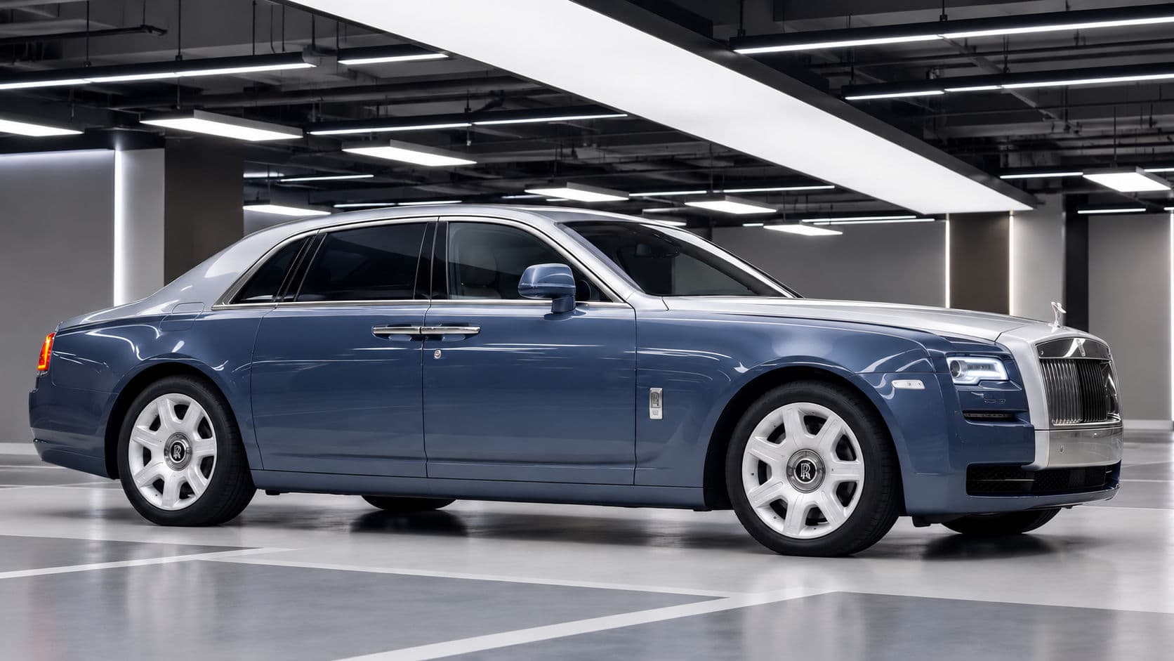 Ghost: Rolls-Royce Ghost 2019, side profile in a bright indoor garage, dusty blue body with silver bonnet, roof and boot, coach doors and illuminated LED headlights