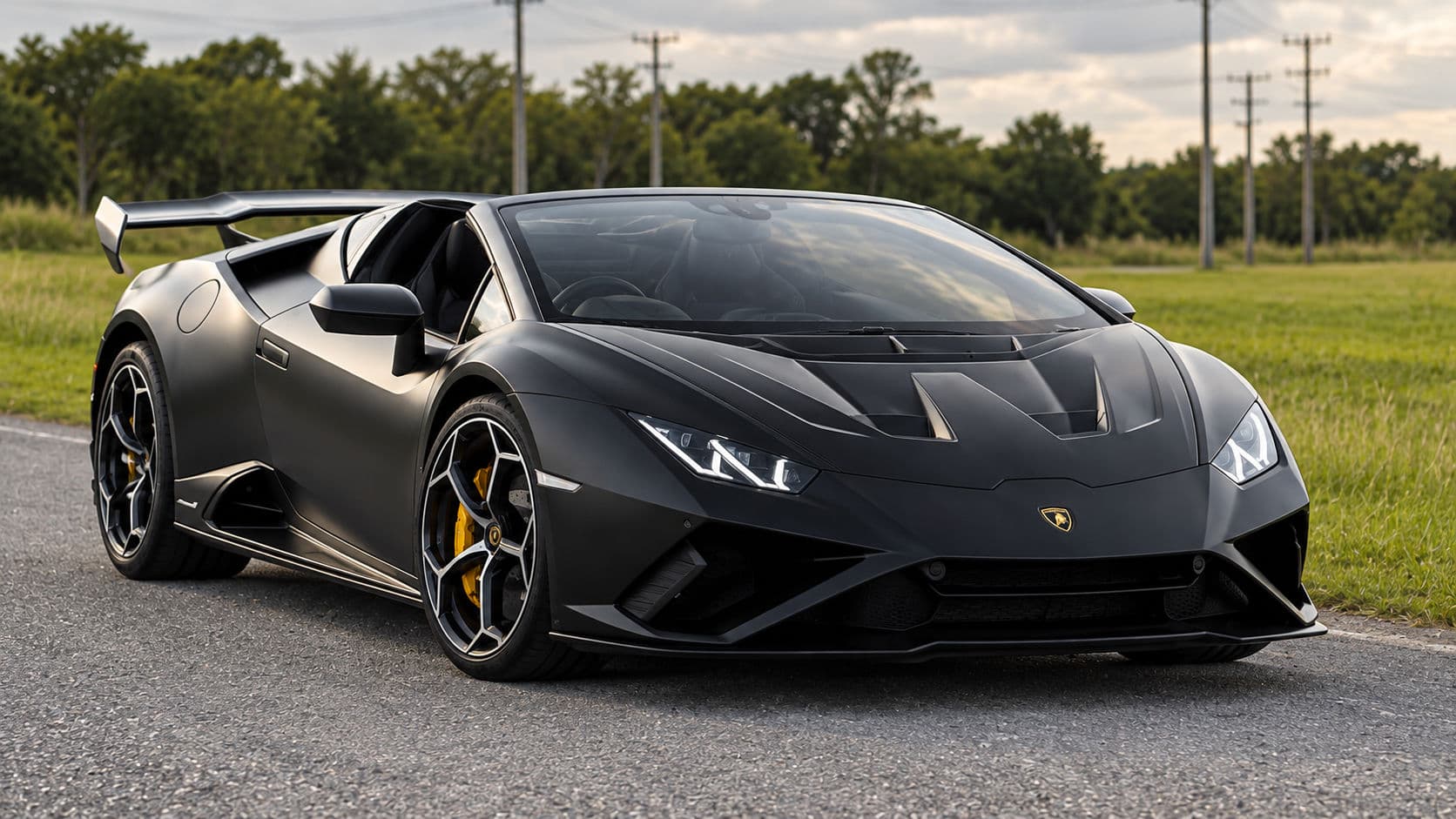 Huracan EVO RWD Spyder: Lamborghini Huracan EVO RWD Spyder 2023 in matte black with the roof down, front three-quarter view on a country road