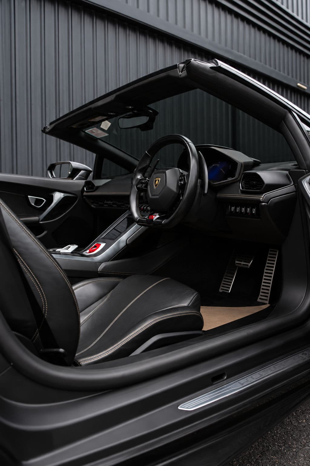 Huracan EVO RWD Spyder: Lamborghini Huracan EVO RWD Spyder 2023 black leather interior with contrast stitching, driver's seat and steering wheel seen through the open door