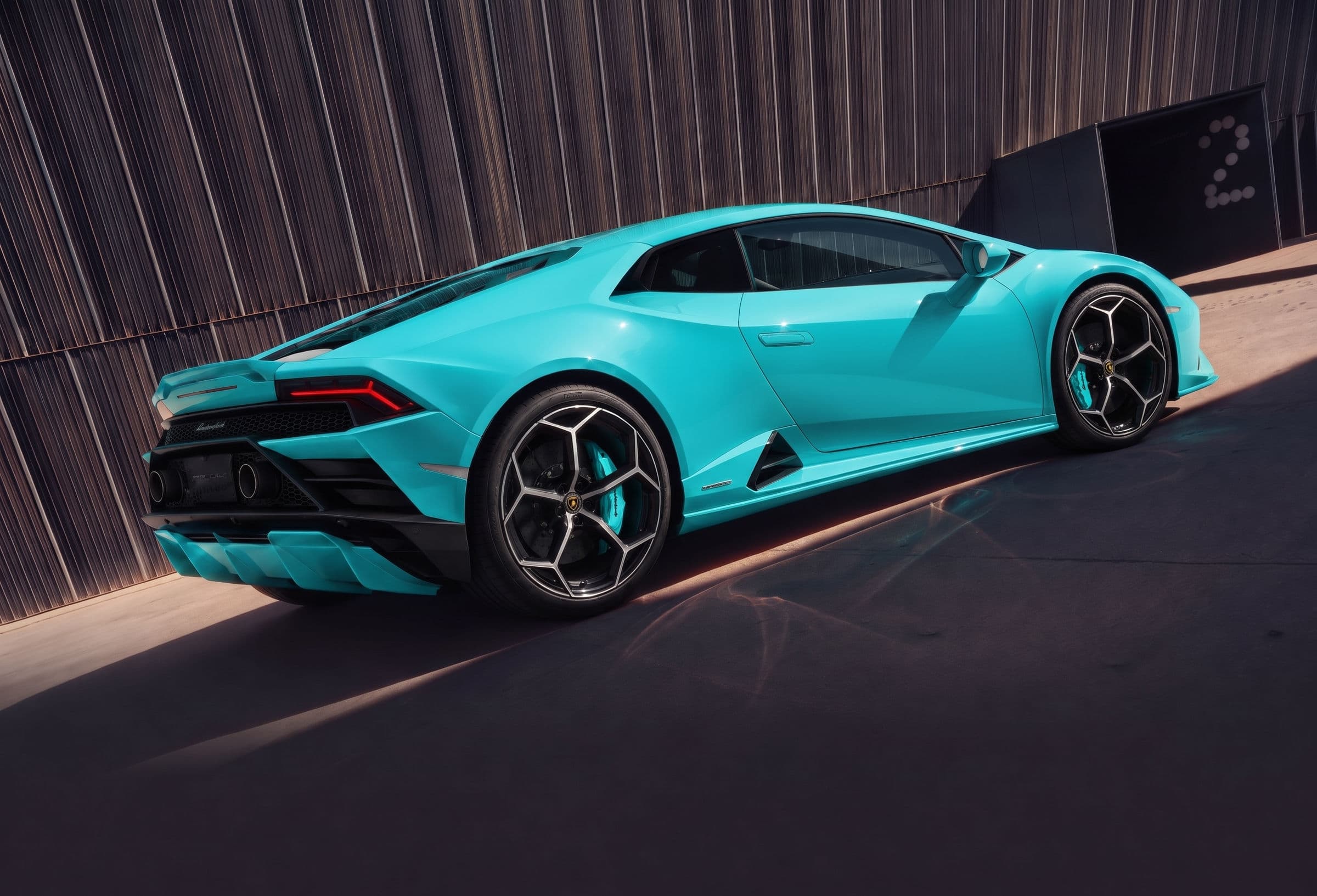 Turquoise Lamborghini parked beside a dark building