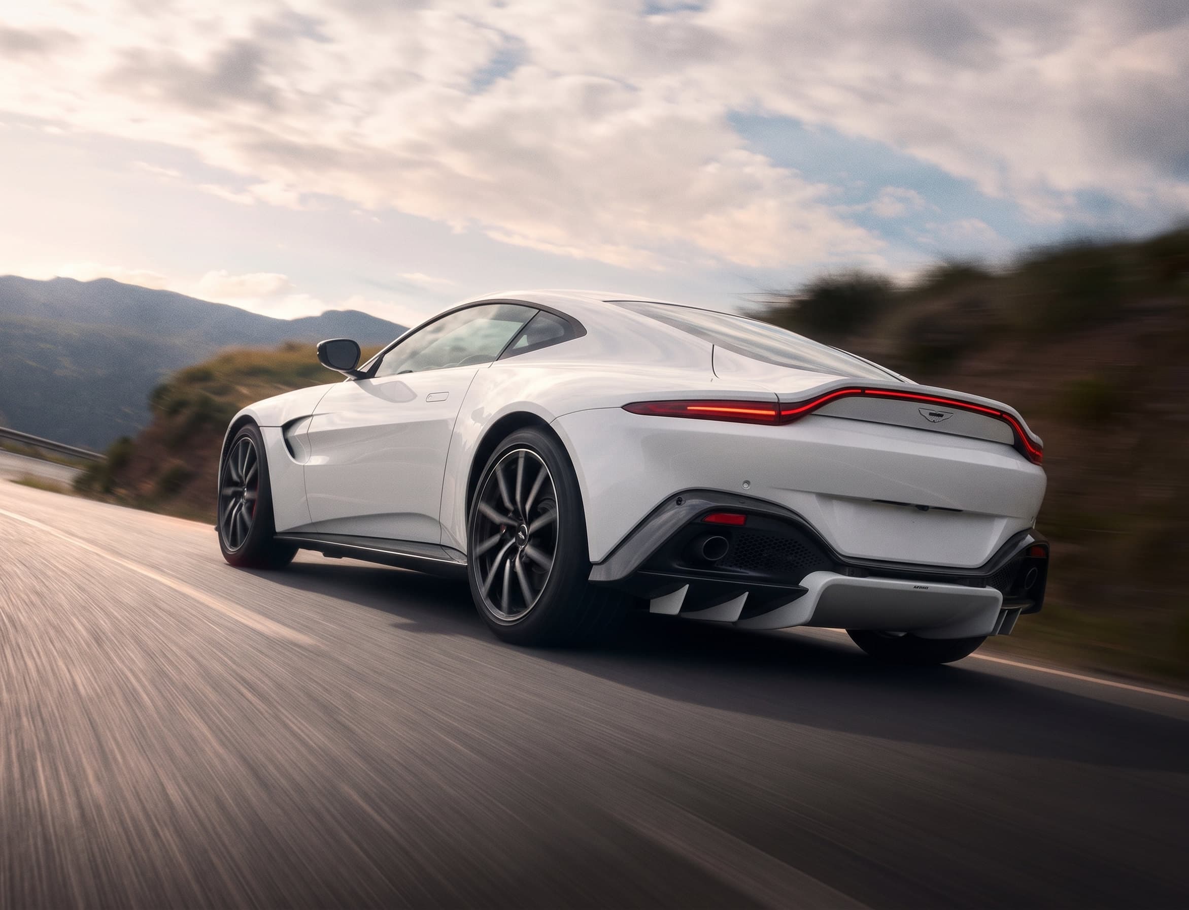 White Aston Martin driving on a mountain road