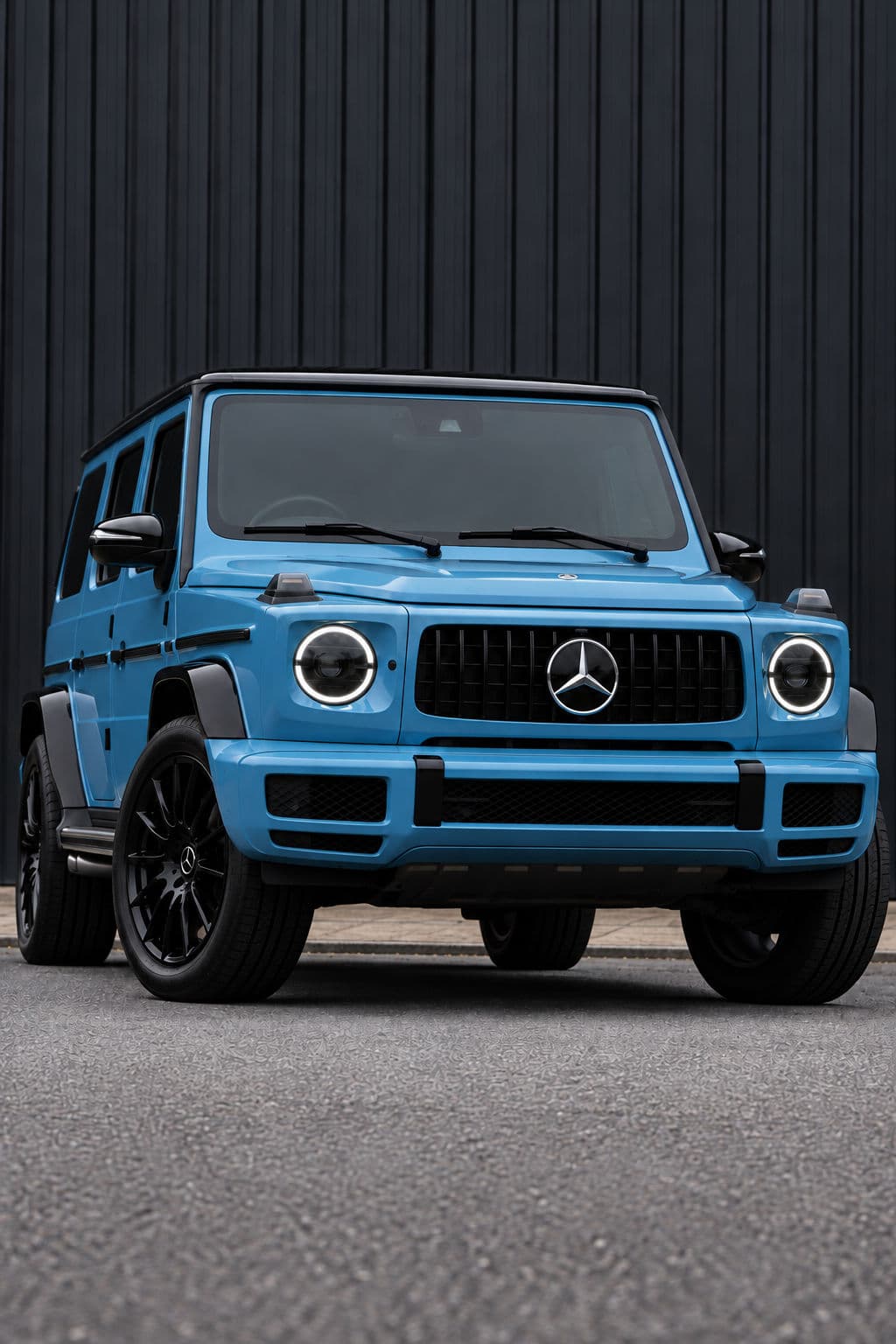 G350: Mercedes-Benz G350 2022 in Vintage Blue, low-angle front three-quarter view with illuminated headlights against a dark wall